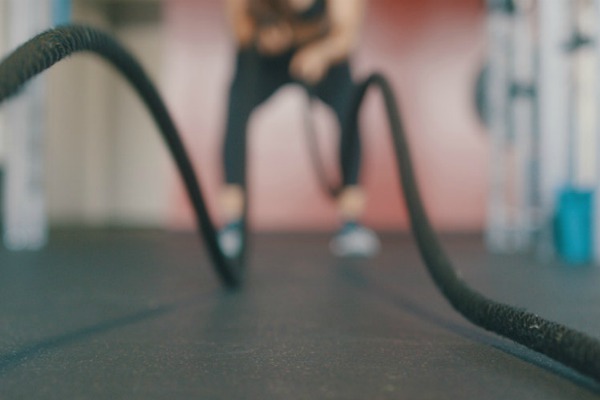 female throwing ropes in gym with distant blur | Starting a Workout Routine? Here's How to Make it Happen https://positiveroutines.com/starting-a-workout-routine/
