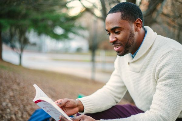 male reading book in park| 11 Productive Things to do With Your Free Time https://positiveroutines.com/productive-things-to-do/