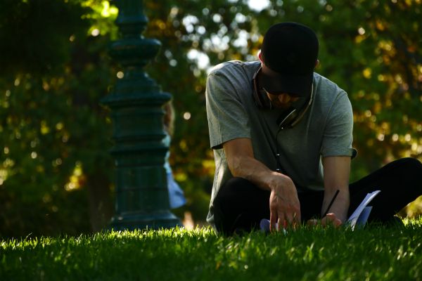 male sitting in grass and writing in journal | 11 Productive Things to do With Your Free Time https://positiveroutines.com/productive-things-to-do/