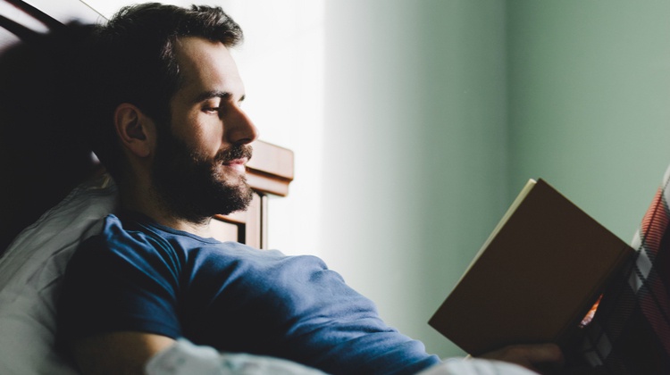 man spending time reading book in bed| 11 Productive Things to do With Your Free Time https://positiveroutines.com/productive-things-to-do/