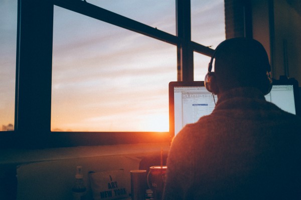 rear view of man focused on desktop computer wearing headphones | 9 Ways to Improve Focus in a Distracted Environment https://positiveroutines.com/improve-focus/
