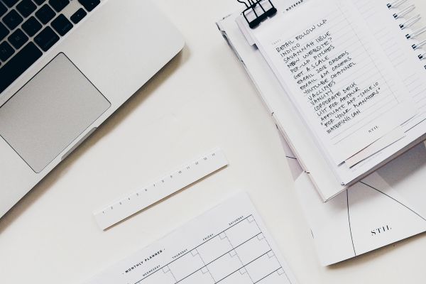 topview of desk with handwritten notes planner and laptop | 10 Minutes to Win The Day: How to Set Priorities https://positiveroutines.com/set-priorities/