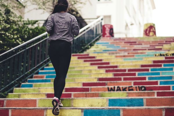 woman jogging up colorful stairs | Starting a Workout Routine? Here's How to Make it Happen https://positiveroutines.com/starting-a-workout-routine/ 