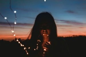 dreamy girl in sunset holding string of small white lights | How to Take Advantage of a Flexible Schedule https://positiveroutines.com/flexible-schedule-tips/