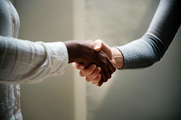 friendly handshake between two people| 11 Kind Acts To Brighten Someone's Day https://positiveroutines.com/kind-acts/