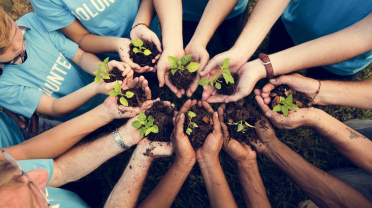 group of volunteers gathered with hands full of seedlings | How to be Selfless This Valentine's Day https://positiveroutines.com/how-to-be-selfless/