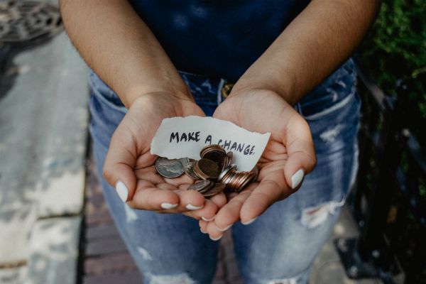 hands holding loose change with note make a change | 11 Kind Acts To Brighten Someone's Day https://positiveroutines.com/kind-acts/