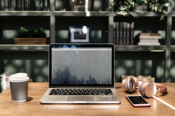 open laptop on sunlit desk beside coffee and headphones | How to Take Advantage of a Flexible Schedule https://positiveroutines.com/flexible-schedule-tips/