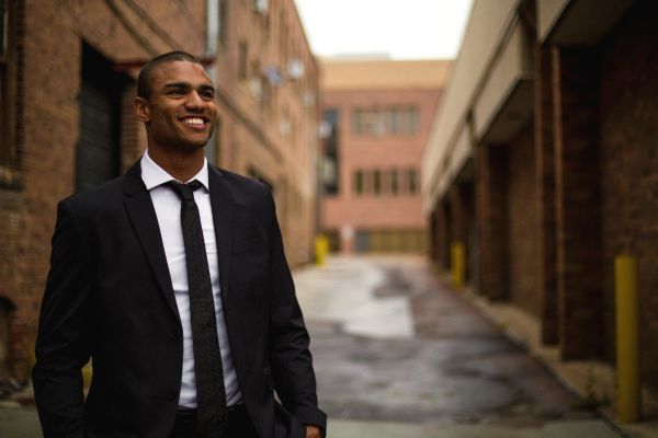 smiling man outdoors in black suit | 7 Easy Ways to Build a More Positive Mindset https://positiveroutines.com/positive-mindset/
