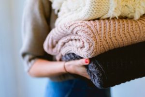 woman carrying stack of folded knit blankets | How to be Selfless This Valentine's Day https://positiveroutines.com/how-to-be-selfless/