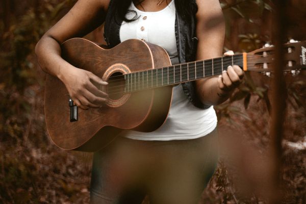 woman-playing-guitar-outdoors | 11 Kind Acts to Brighten Someone's Day https://positiveroutines.com/kind-acts/