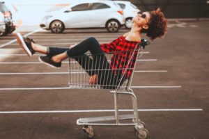 carefree young woman sitting in shopping cart | The Best Free Budgeting Apps to Hit Your Goals https://positiveroutines.com/free-budgeting-apps/