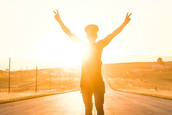 man in sunset holding hands in air | The Curious Case of Success and Luck https://positiveroutines.com/success-and-luck/