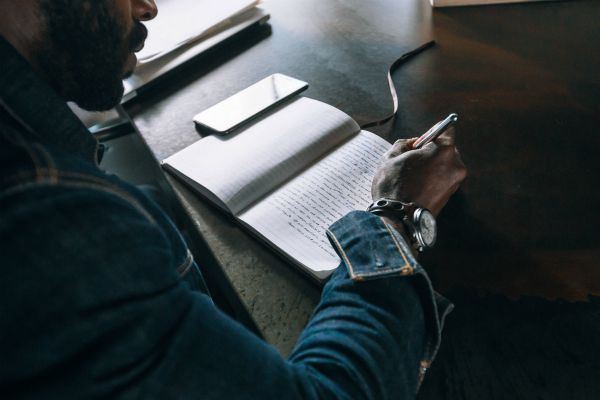man writing in journal | Productivity on Paper: The Happiness Planner vs. Panda Planner https://positiveroutines.com/the-happiness-planner-panda-planner