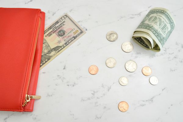 orange wallet on marble table with US dollars and coins | Productivity on Paper: The Happiness Planner vs. Panda Planner https://positiveroutines.com/the-happiness-planner-panda-planner