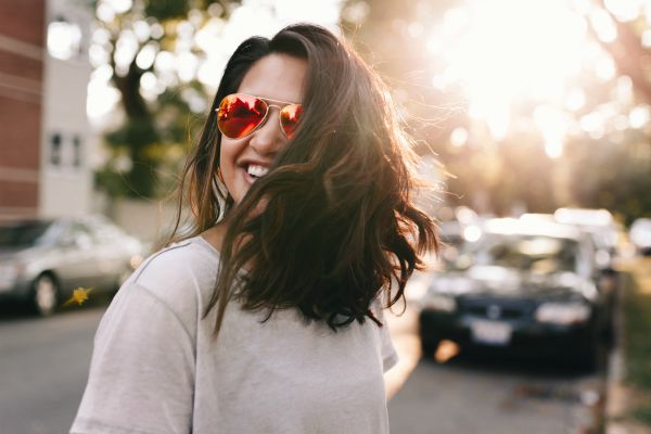 smiling woman outdoors wearing sunglasses | The Curious Case of Success and Luck https://positiveroutines.com/success-and-luck/