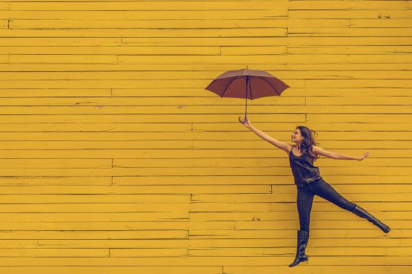 woman jumping with umbrella | What is Procrastination? Causes, Effects, & How to Stop Procrastinating https://positiveroutines.com/what-is-procrastination/