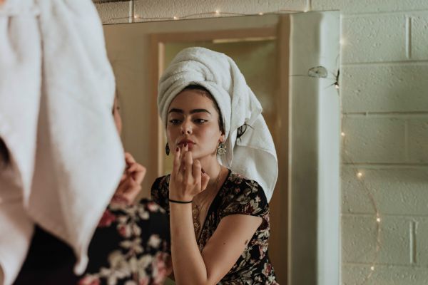 woman looking at lips in mirror applying makeup | 13 Gratitude Journal Prompts to Try This International Day of Happiness https://positiveroutines.com/gratitude-journal-prompts/