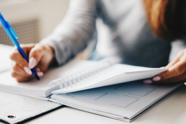 closeup woman writing in planner | What Is Organization? How to Declutter and Organize Your Life https://positiveroutines.com/what-is-organization/