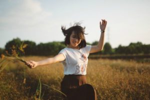 happy woman in field | Why is Nature Important to Happiness https://positiveroutines.com/why-is-nature-important-happiness/