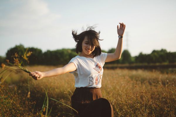 happy woman in field | Why is Nature Important to Happiness  https://positiveroutines.com/why-is-nature-important-happiness/