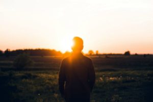 man looking out into sunrise | 7 Science-Backed Secrets of a Productive Morning Routine https://positiveroutines.com/productive-morning-routine/