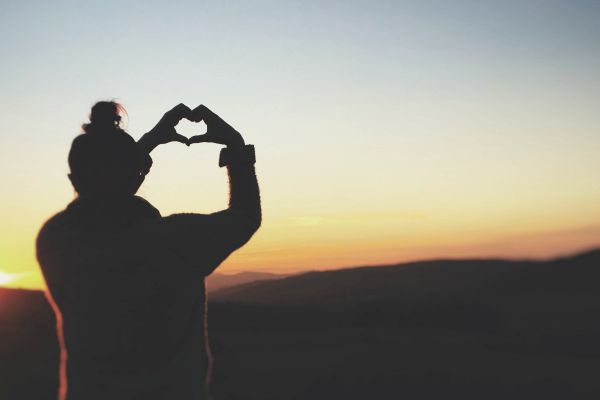 woman holding heart hand gesture in sunset | Why is Nature Important to Happiness  https://positiveroutines.com/why-is-nature-important-happiness/