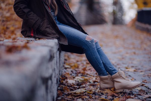 woman sitting on stone wall with leaves beneath feet | Why is Nature Important to Happiness  https://positiveroutines.com/why-is-nature-important-happiness/