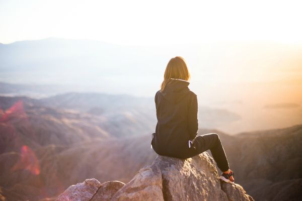 woman sitting on cliff overlooking sunset | The Best Guided Meditations for Sleep, Stress, and More https://positiveroutines.com/best-guided-meditations/