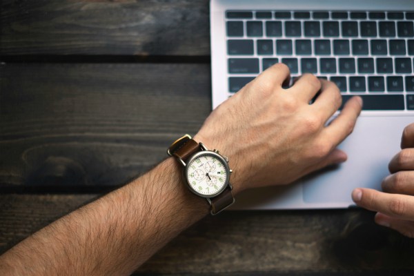 closeup mans watch as he works on laptop | Why You Don't Need a Time-Management Plan  https://positiveroutines.com/time-management-plan/