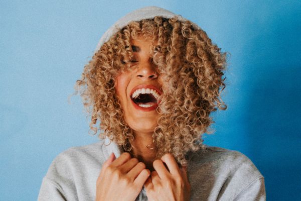 happy laughing woman in hooded sweatshirt | Why Does Exercise Make You Happy  https://positiveroutines.com/why-does-exercise-make-you-happy/