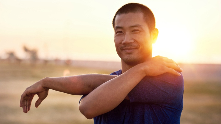 happy man stretching arms in sunset | Why Does Exercise Make You Happy https://positiveroutines.com/why-does-exercise-make-you-happy/