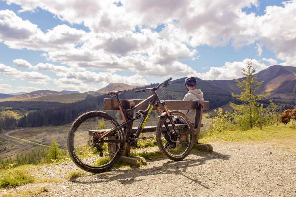 man taking break from bike ride overlooking mountains | Why Does Exercise Make You Happy  https://positiveroutines.com/why-does-exercise-make-you-happy/