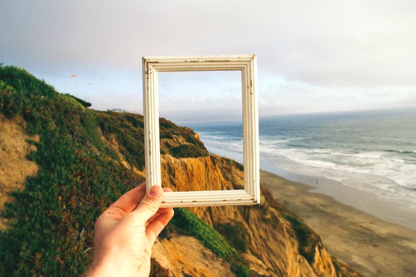 person holding empty frame up against shoreline | 7 Ways Downtime at Work Makes You More Productive https://positiveroutines.com/downtime-at-work