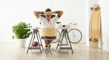 relaxed man working at desk beside bike and skateboard | 7 Ways Downtime at Work Makes You More Productive https://positiveroutines.com/downtime-at-work