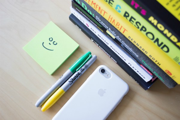 smiley face on sticky note beside markers iPhone and stack of books | Why You Don't Need a Time-Management Plan  https://positiveroutines.com/time-management-plan/
