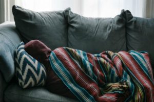 person napping on couch with blanket | Is Work and Life Balance Even Achievable in 2019? https://positiveroutines.com/work-and-life-balance-tips/