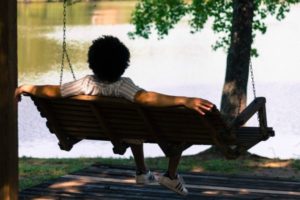 person relaxing on wooden bench swing | Is Work and Life Balance Even Achievable in 2019? https://positiveroutines.com/work-and-life-balance-tips/