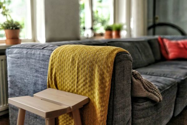 inviting grey couch with yellow blanket | 7 Natural Ways to Boost Energy, According to Science https://positiveroutines.com/natural-ways-to-boost-energy/