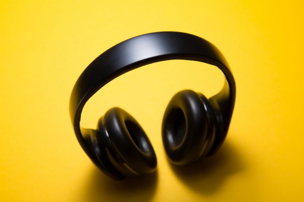 wireless headphones on yellow background | 7 Easy Ways to Create a Healthy Work Environment https://positiveroutines.com/work-environment-tips/