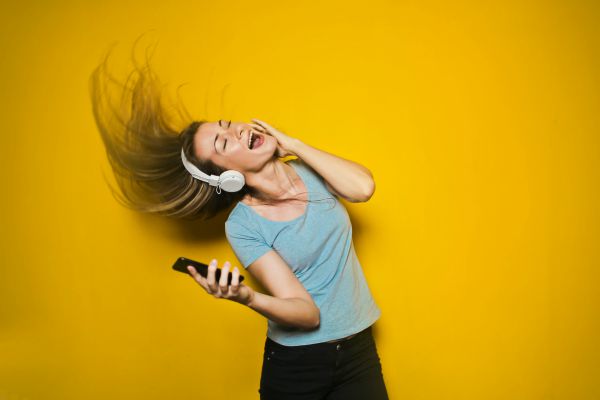woman with headphones singing and flipping hair | 7 Natural Ways to Boost Energy, According to Science https://positiveroutines.com/natural-ways-to-boost-energy/