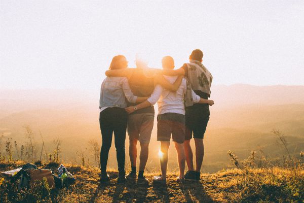 four friends embracing before sunset | Why Making Friends at Work Matters and How To Do It https://positiveroutines.com/making-friends-at-work/