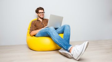 happy man using laptop on yellow beanbag | Our Best Blog Posts of 2019 To Make You Happier Immediately https://positiveroutines.com/best-blog-posts/