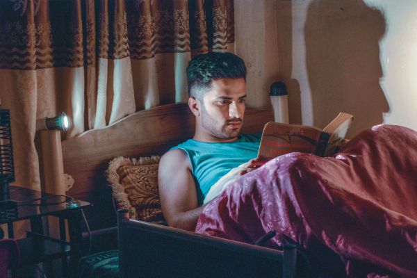 man reading book in bed | The Happiness-Boosting Magic of Evening Routines https://positiveroutines.com/evening-routines/